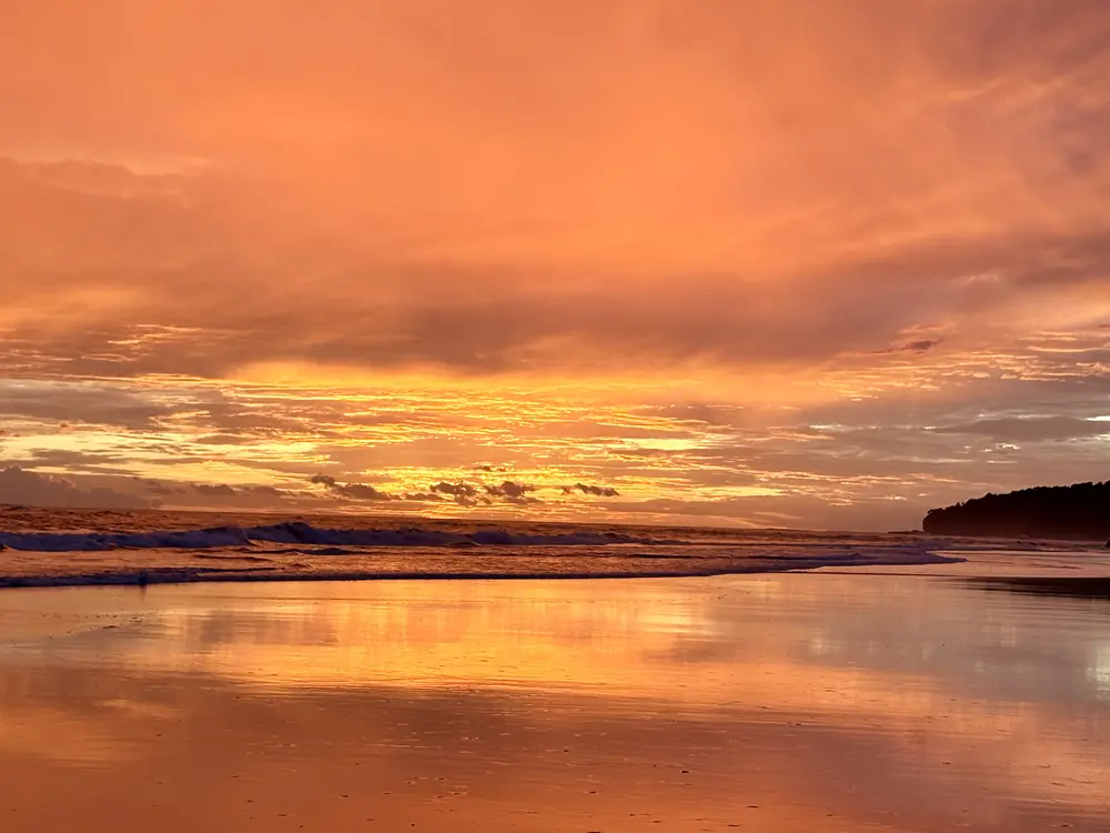 Afterglow over the headland, doubled on the sand