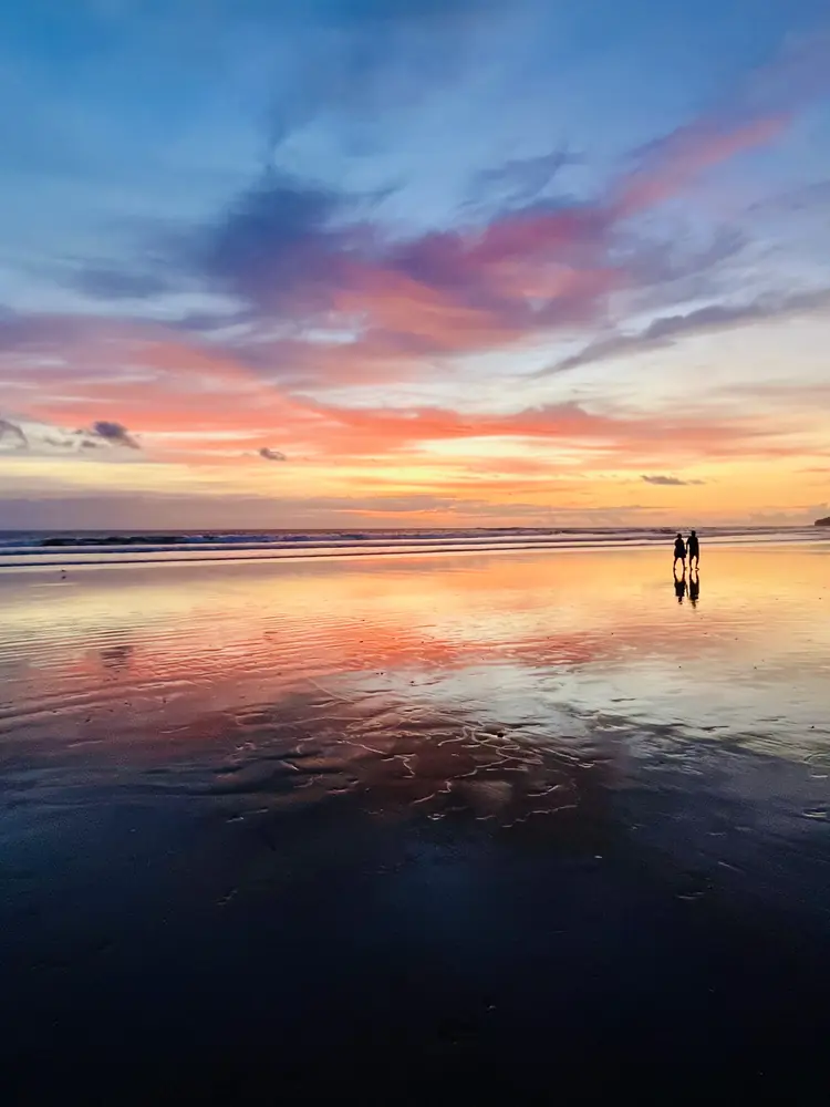 Pink and purple sky over two walkers