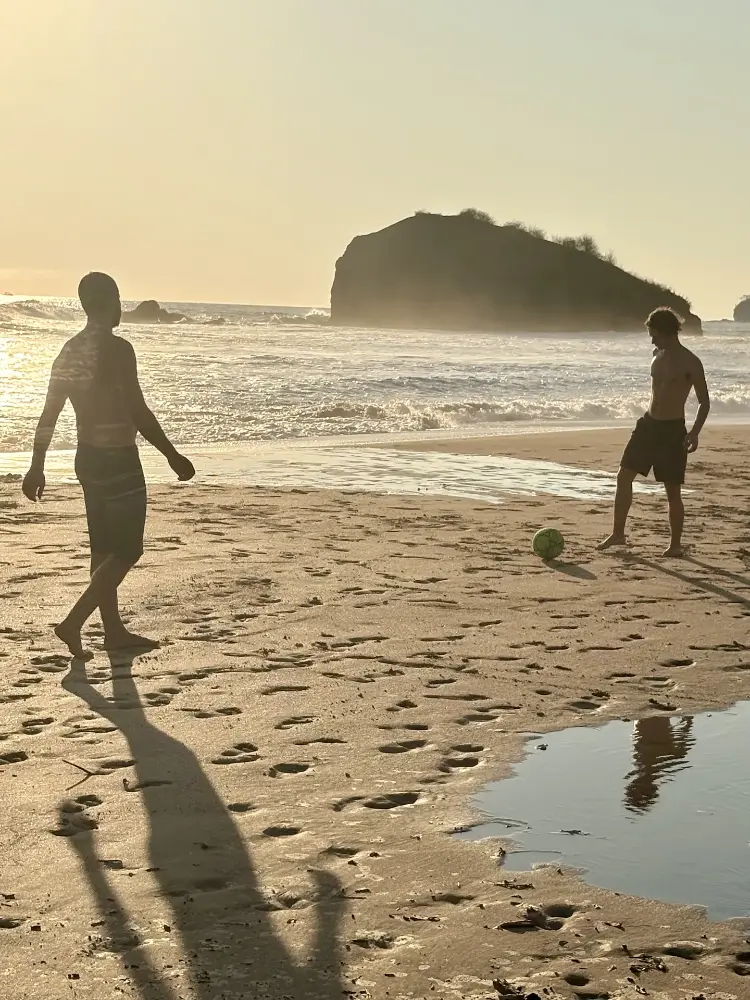 Beach soccer at golden hour with the big rock behind