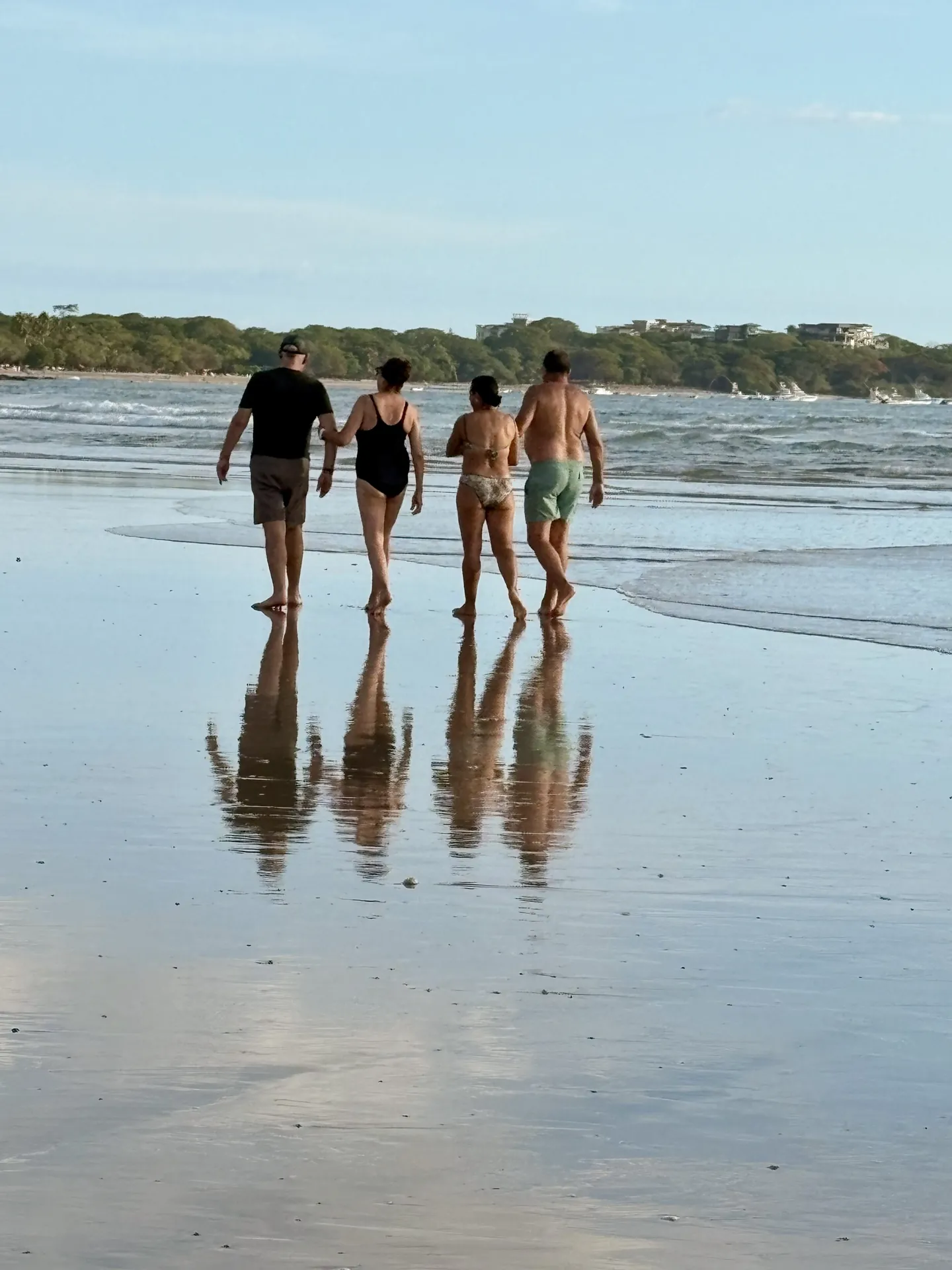Friends walking on the mirror-wet sand