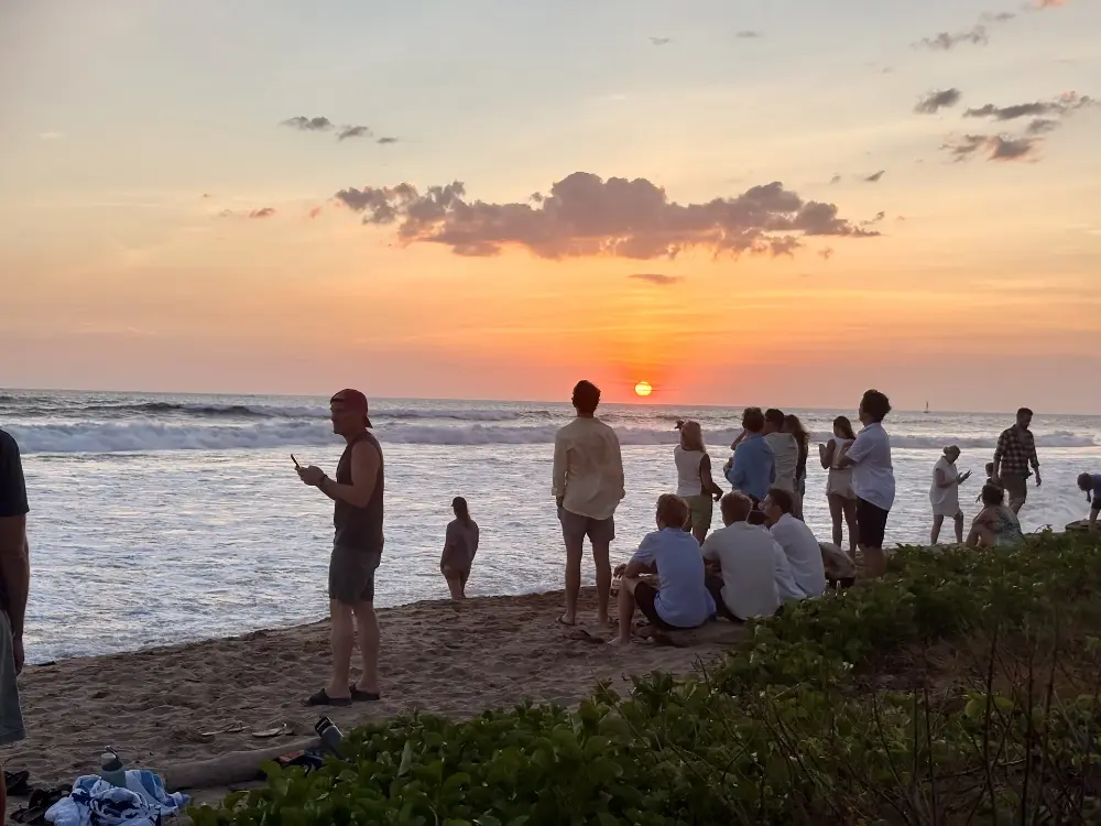 Neighbors and visitors gathering on the beach to watch the sunset